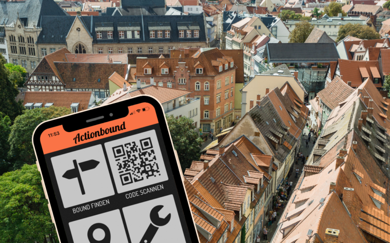 Im Hintergrund ist ein Foto von der Erfurter Altstadt, im Vordergrund sieht man ein Smartphone, auf dem die Rallye geöffnet ist.
